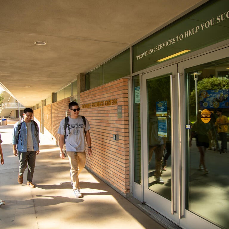 Three students walk toward the Academic Resource Center doors